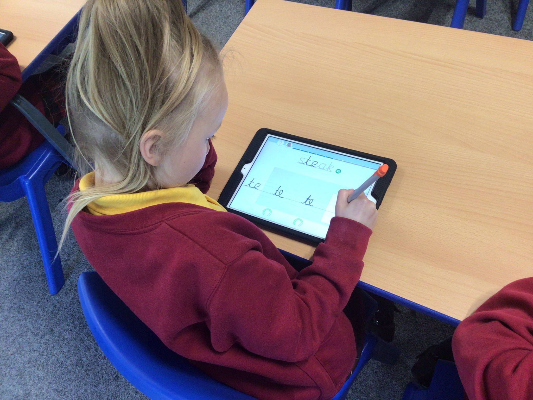 Child at St James' Primary writing on Kaligo App