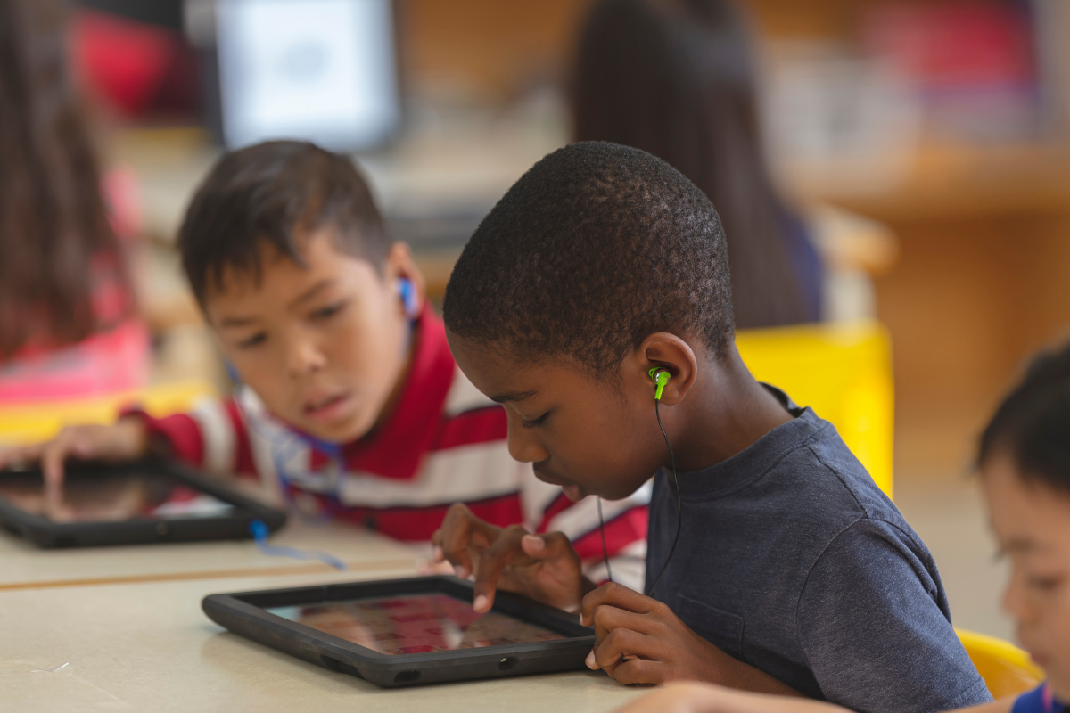 enfants avec tablettes et écouteurs en classe
