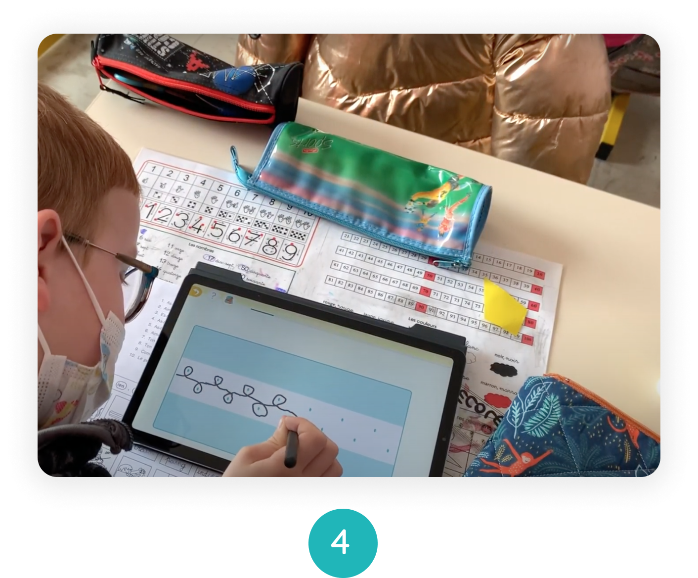 Ein Junge zeichnet mit dem Stift Locken auf seinem Tablet. Er sitzt an seinem Schreibtisch und trägt eine Brille